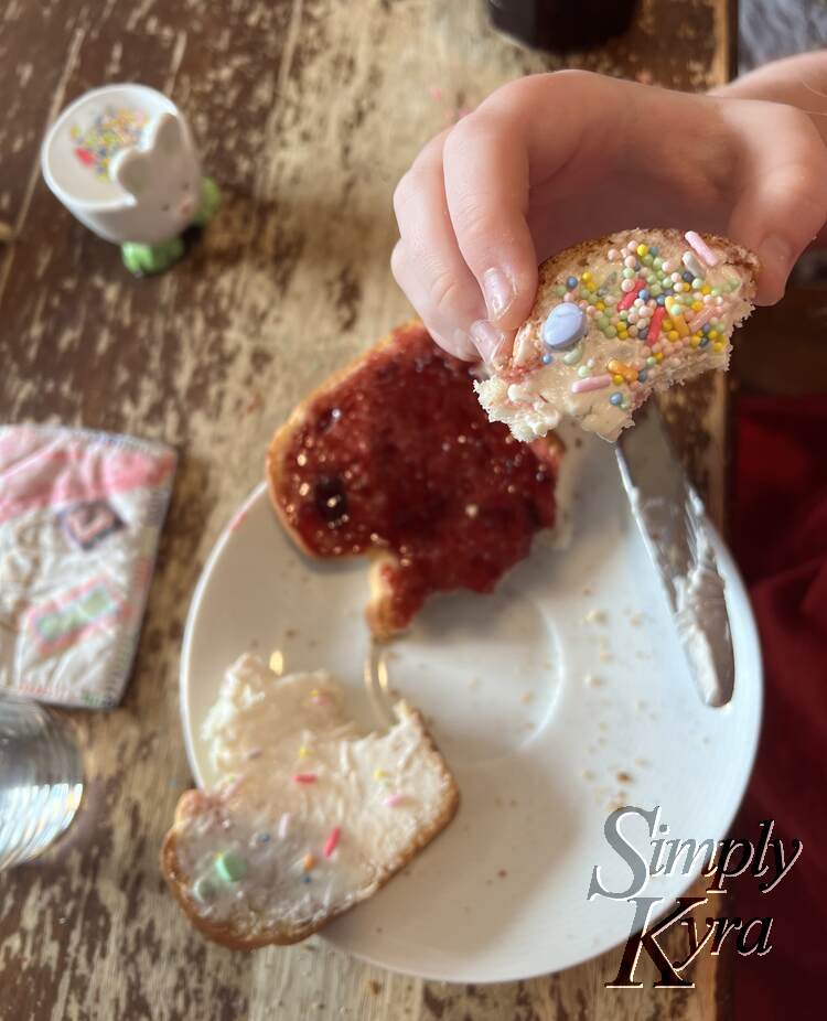 Image shows a piece of the cream cheese and sprinkled coated toast being held up while the remaining two pieces and bunny looks on from the blurred out background.