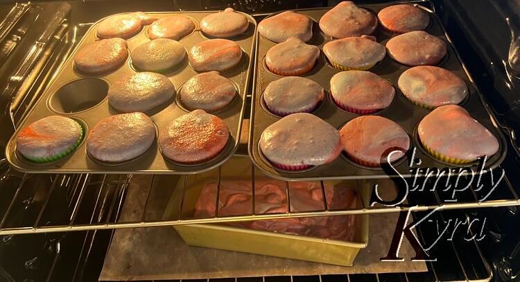 Same oven as before with the same two pans on the top side by side. Now the cupcakes are overfilling as they filled with the batter all the way. Underneath is a single loaf pan about a third full. 