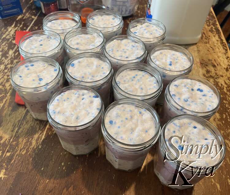 Image shows all fourteen jars with different amounts of each batch making a white top and bottom layer with a purple one in the center. 