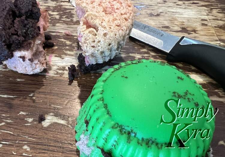 Image shows a green silicone cupcake liner flipped inside out with a steak knife a cut open cupcake behind it showing the layers.