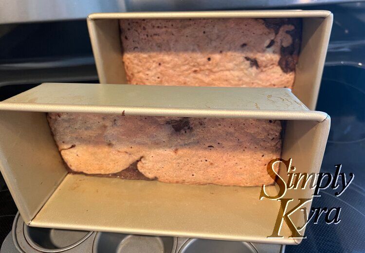 Two loaf pans on its side cooling with a thin layer of brownie and angel food cake at the bottom. 