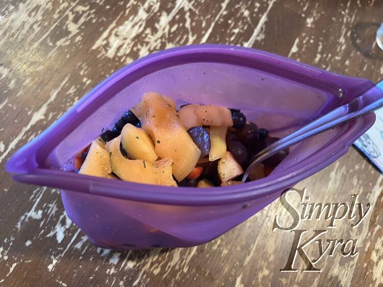 Image shows a purple slasher bag with mint flecked fruit and a spoon.