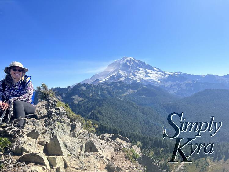 Me sitting on rocks to the side with lake Eunice and Mount Rainier/Tahoma in the background.