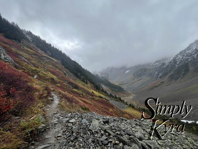 Similar image as before but now highlighting the landscape with the colorful red, yellow, and green against the greys of the clouds and rocks.