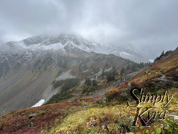 Image shows a yellow, red, and green hill slowly stretching to the white and grey mountain. 