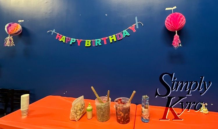 Image shows an orange lined table with food and decorations,