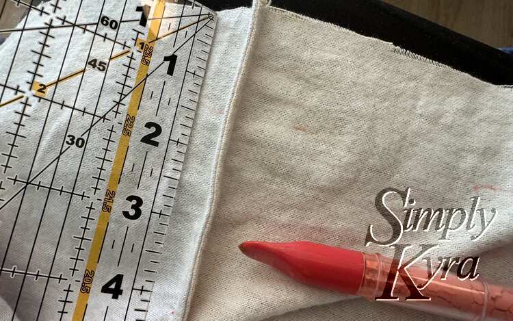 Quilting ruler is placed next to seam marking distance from the raw top. Chalk roller pen is next waiting to mark where the folds should end for a channel.