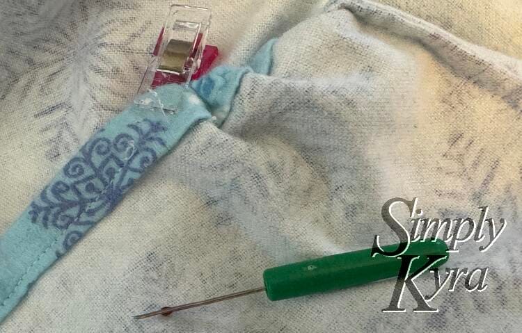 Image shows a seam ripped seam with sewing clip marking the space and seam ripper to the side.