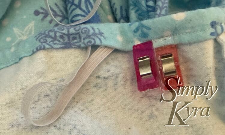 Loop of elastic is sticking out of the hole with two clips next to it out of the way but marking the hole.