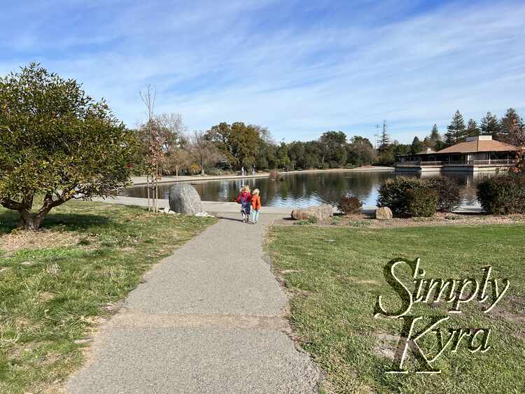 Image shows the kids in the distance approaching the lake with the community center in the background.