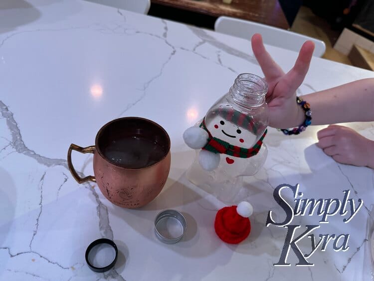 Image shows that open and emptied festive ginger beer bottle standing next to a Ginger Lab mule glass with opened lids next to it. It has bunny ears given by Ada. 