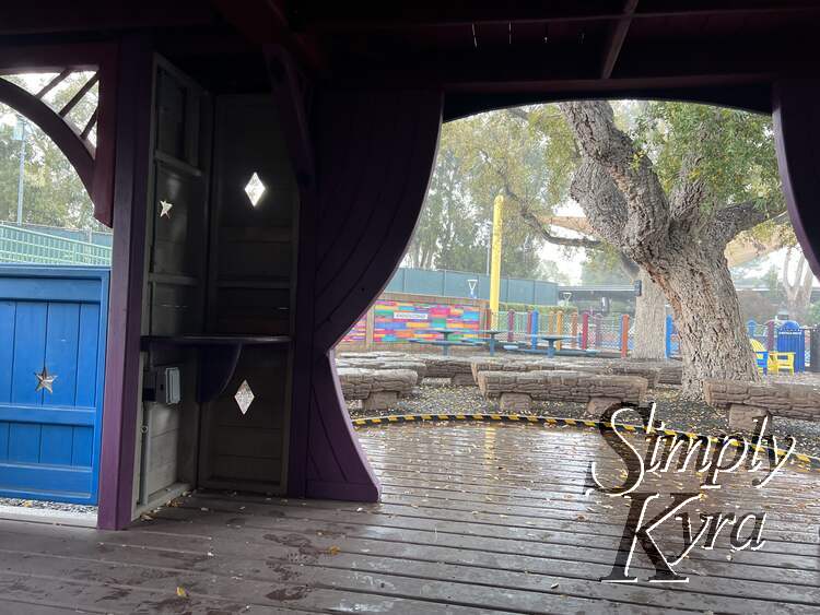 Image is looking out from a chair in the lower level of the playhouse showing the stage, benches to watch from, and kindness wall. 
