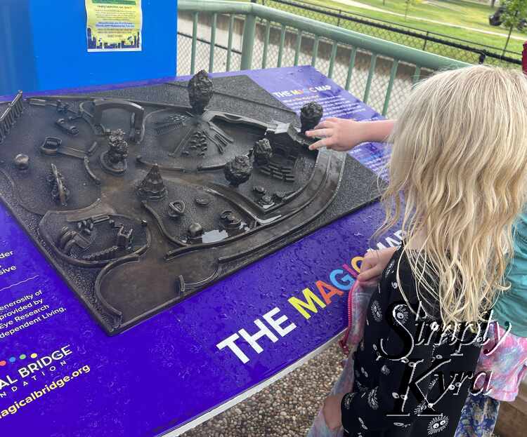 Image shows the girls looking at a wet metallic three dimensional map. 