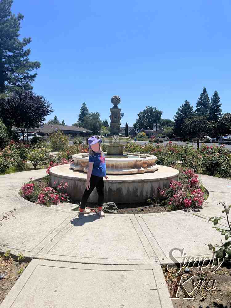 Ada posed in front of the fountain with roses and pathways around. 