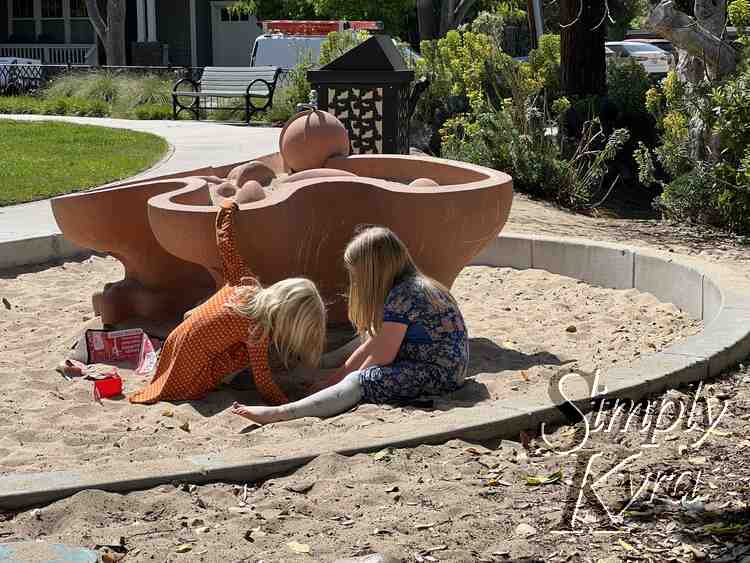 Image shows the girls digging for the 'wet' sand in front of the turned off water feature.