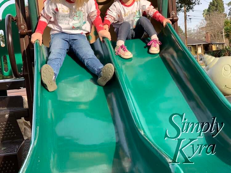 Image shows a side by side plastic slide with the two girls at the top about to go down. 