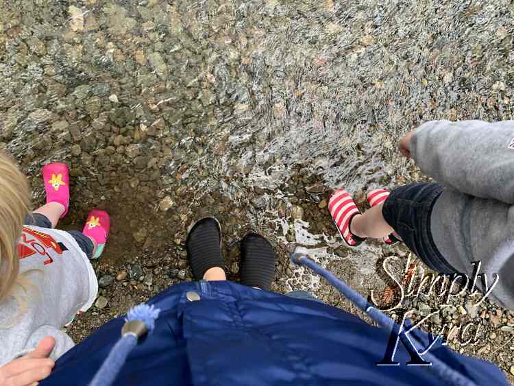 Image is taken looking down at mine and my girls water shoes in the water.