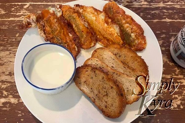 Image shows four pieces of rye toast, four browned and cheese wrapped pickles, and a side of tart yogurt dip. 