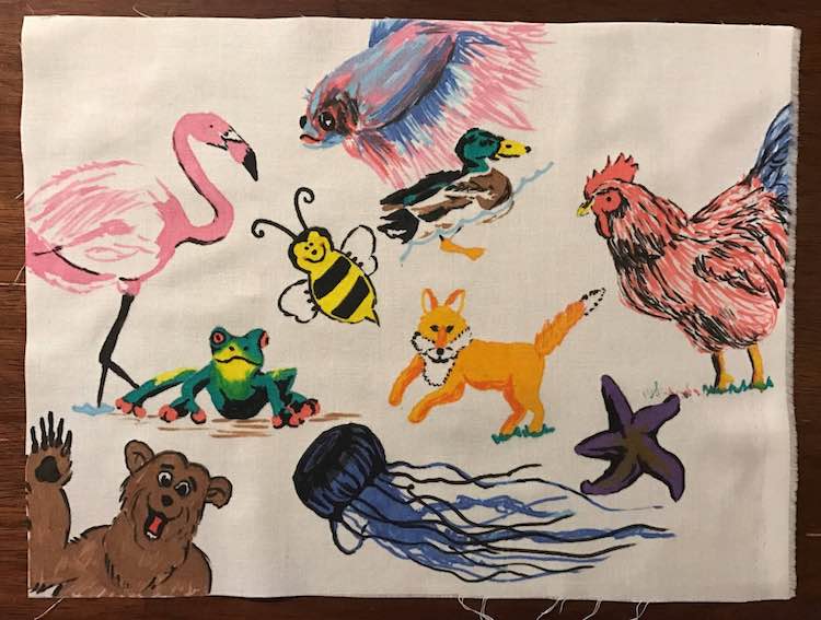I used my fabric markers to draw animals on a swatch of muslin fabric a bit bigger than 9 by 12 inches and then used an iron to set the ink.