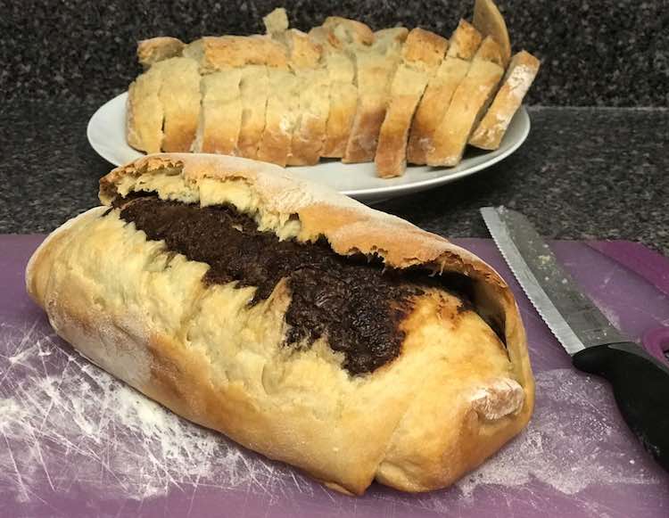 Two loaves fresh from the oven and cooled for 5 minutes. Plain bread is sliced and the Nutella bread is about to be sliced next.