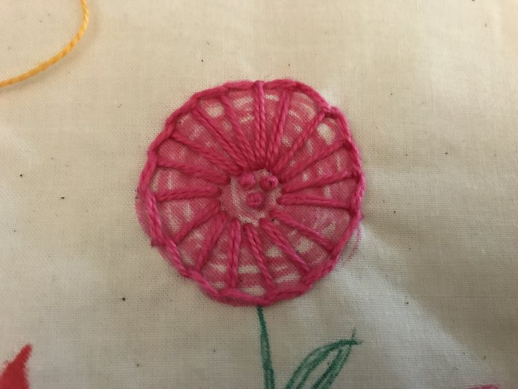 I wanted something simple and open to let the pink fabric marker show through yet still differentiate between the center and it's petals. I used three french knots to show the center and used a blanket stitch for the petals.