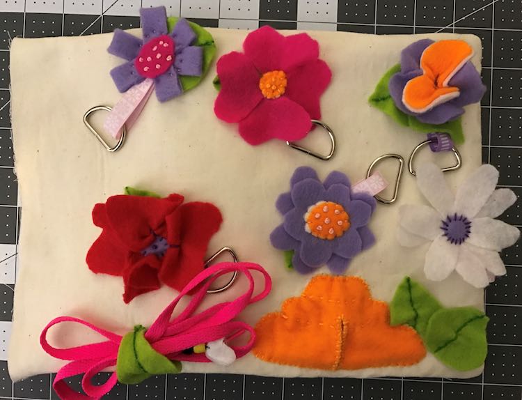 I then sewed my flowers over the connected ribbons making sure the D-Rings were available. I also sewed down a bee hive to put bumblebee in and added the shoelace with a 'bee' at the end.
