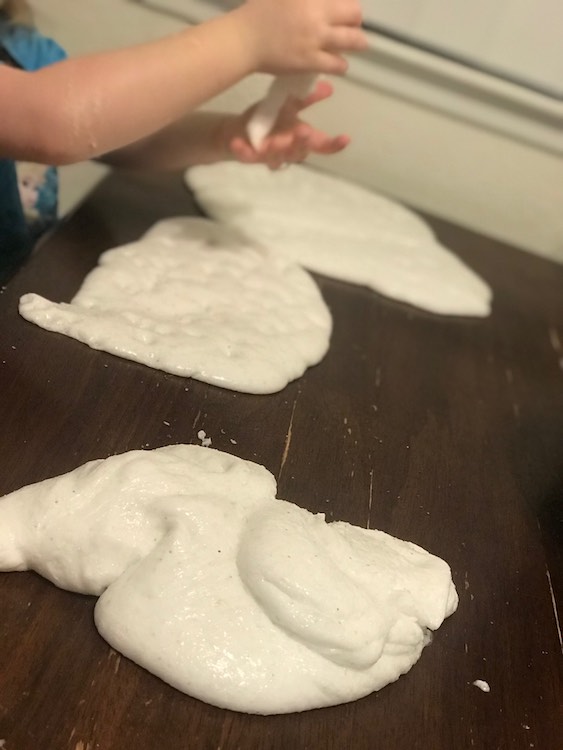 Ada pulling and holding snow slime while the rest sits on the table.