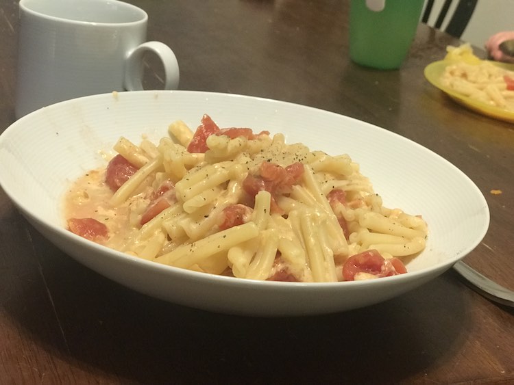 Hot pasta, tomatoes, and cheese seasoned with pepper and ready to eat.