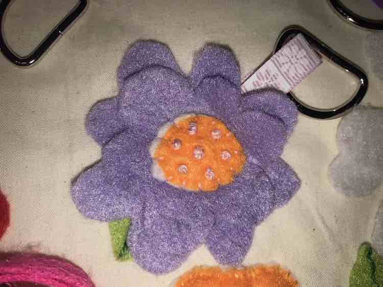 Two different sized purple flowers with a center laid overtop and then attached with french knots.