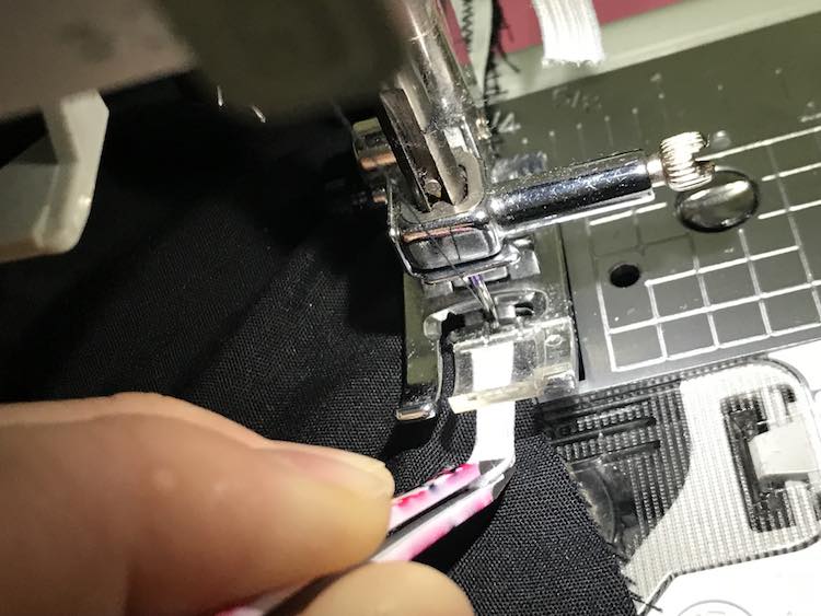 Using tweezers to stretch the elastic while sewing it down.