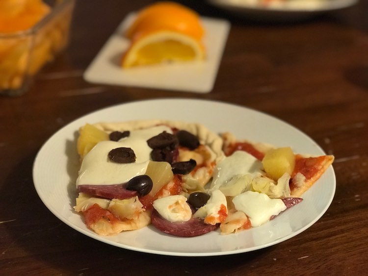 A couple pieces of pizza. Topped with tomato sauce, salami, canned pineapple chunks, black olives, and mozzarella.