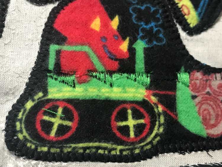 So I used green thread to stitch across the line being careful to not go over the black or the dinosaur's hand.