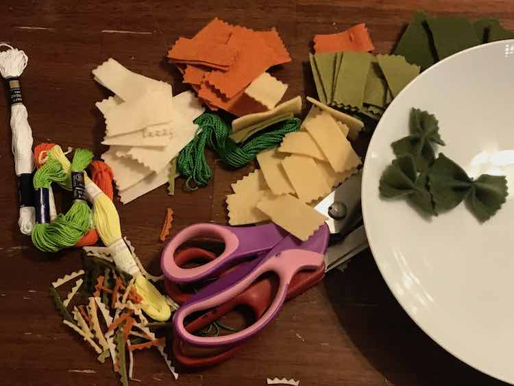 All the steps in making the pasta is shown. To the left is the embroidery floss and cut off crinkles. The center shows the rectangular felt pieces with the crinkled ends along with my pinking shears and fabric scissors. To the right is a bowl with three perfectly green bow-tie pasta.