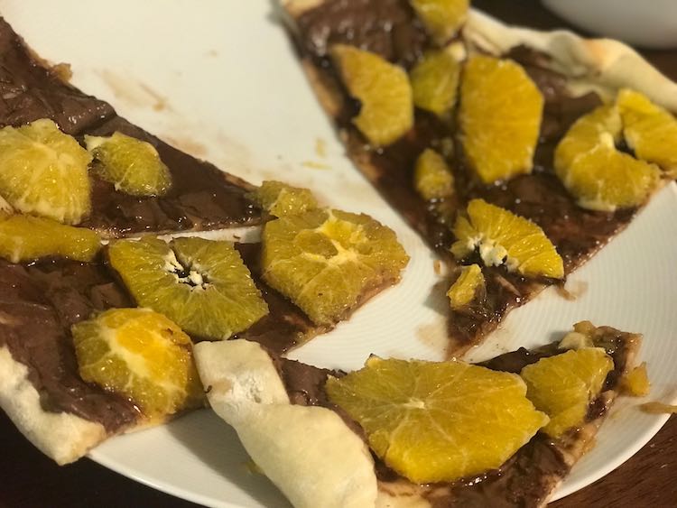 Several slices of Nutella and sliced orange coated pizza on a white plate.
