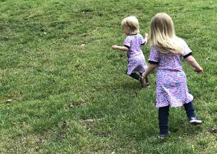 Back of both girls can be seen as they run in the grass; making them a bit blurred in places. 