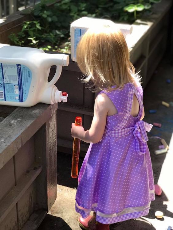 Here Ada used an emptied bubble wand container to hold, transport, and dump the water.