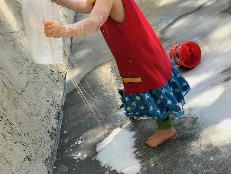 Zoey holding up the oobleck container as threads of it drip down.