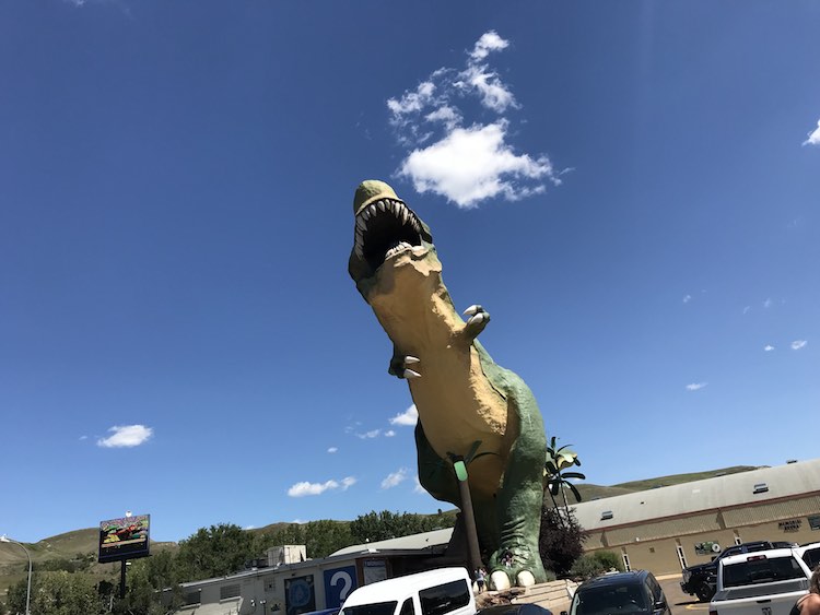 The giant dinosaur towering over the cars and people. If you look closely you may be able to see the guardrail and people inside the mouth.
