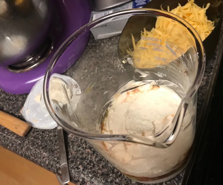 Once you took all the store-bought layers out of the fridge, mixed the cream cheese layer, and grated the cheese it's time to start layering the layers in your beaker.