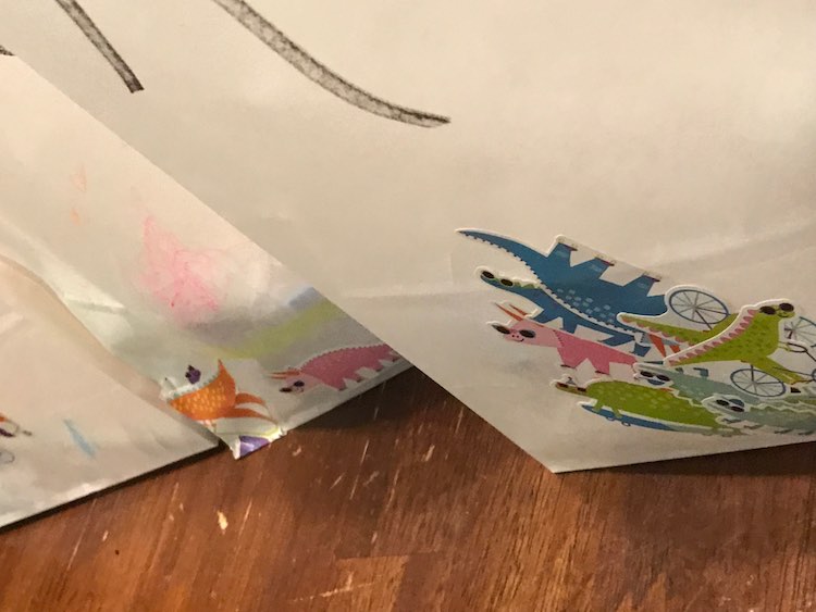 I bought a large package of white paper bags so Ada could decorate them. I went through and wrote all the names of the guests on them and then passed them in sets of one or two to Ada to decorate with crayons (ignored) and stickers.