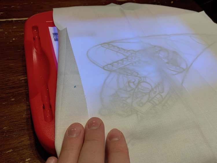 Coloring page and fabric overtop of a light box so tracing would be easier.