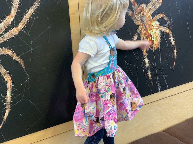 Zoey in the dress in front of spider posters.