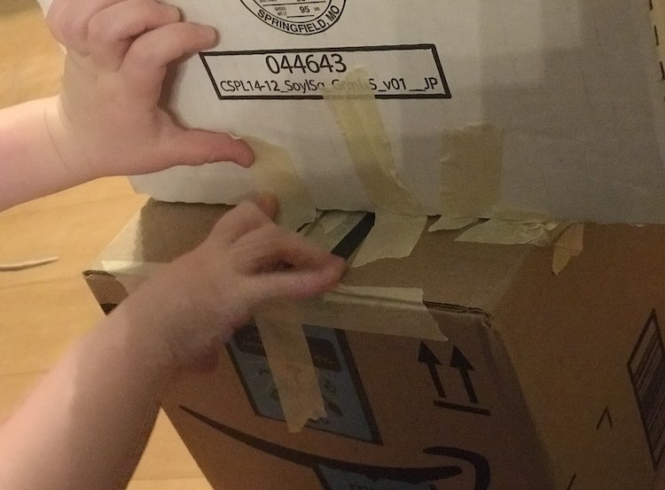 Shows Ada holding the tape onto the box.