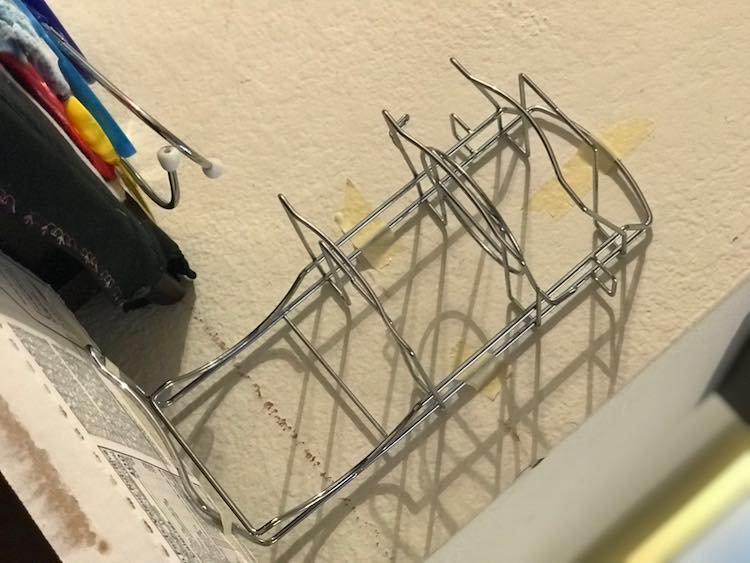 The top of the box and side of the main kitchen set is showing. The main feature is a metal stand taped to both the box and the wall behind it.