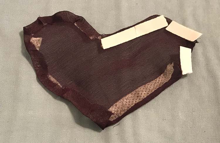 Underside view of the heart showing all edges folded in and kept in place with double sided tape. The upper right corner of the heart shows white tape along the edge as the paper on that tape wasn't removed yet.