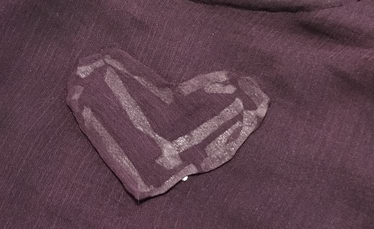 The right side of the heart shows with the rest of the camisole behind it. You aren't able to see the holes behind the heart but you can see all the tape used through the fabric. 