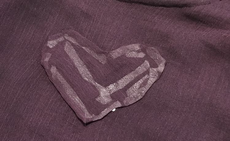 The right side of the heart shows with the rest of the camisole behind it. You aren't able to see the holes behind the heart but you can see all the tape used through the fabric.