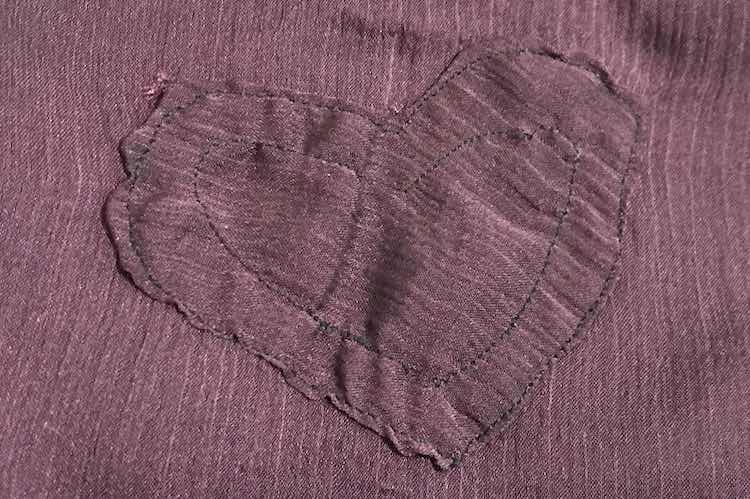 Closeup of the heart shows the lines going angled across rather than down like the base camisole. No tape is showing through the heart and the stitches are keeping the heart in place.