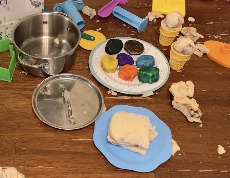 Empty pot, playdough sandwich on a blue plate, plate of several different hued solid colored cookies, and two ice cream cones.