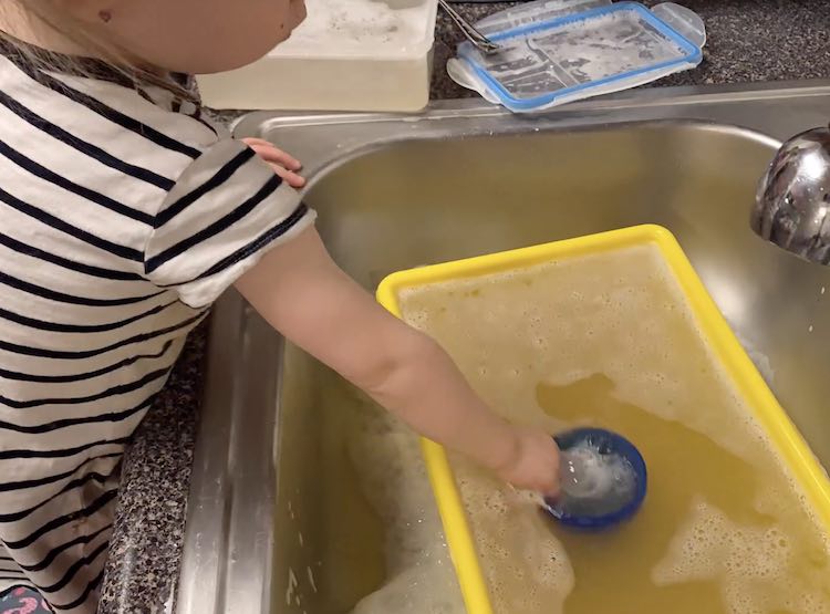 Zoey playing with soapy water in the sink.